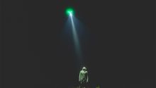 Photo illustration of a light shining down from the sky on a person to accompany the article Are Aliens Real?